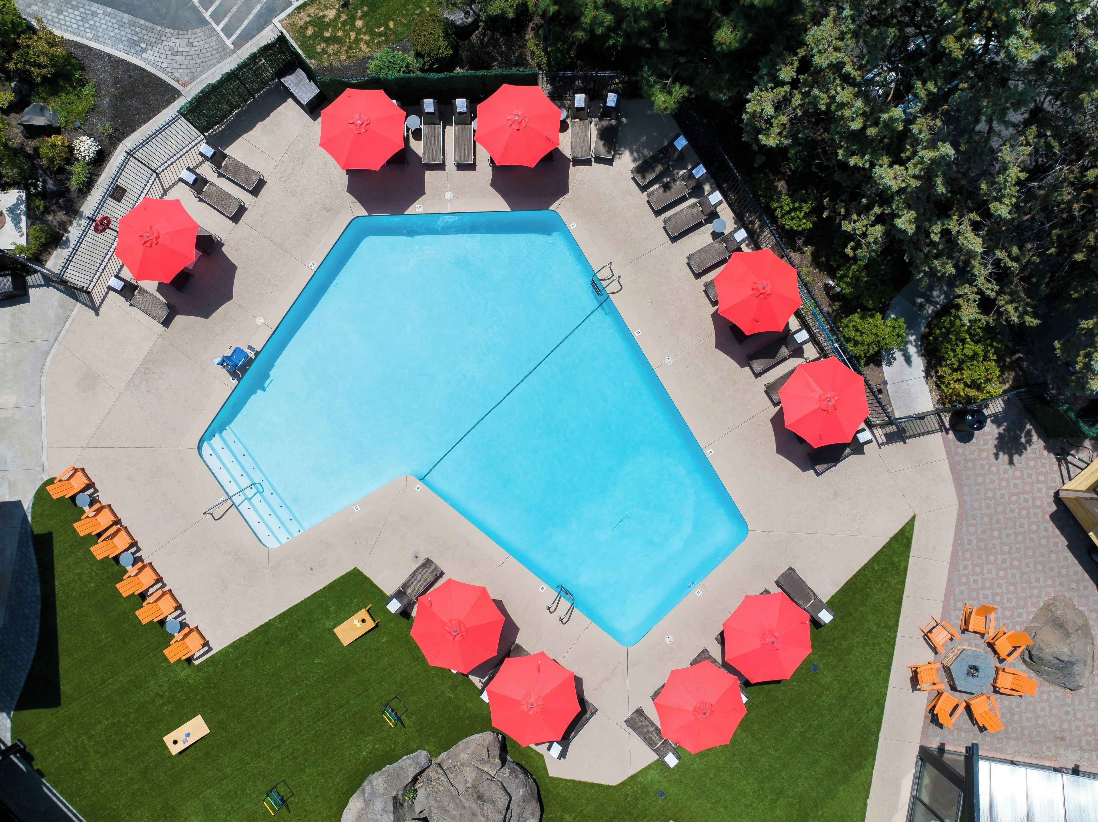 An aerial view of a swimming pool surrounded by lounge chairs and umbrellas.