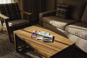 Ein Hotelzimmer mit einem Holztisch, einem karierten Sessel und einem Sofa mit passenden Kissen.