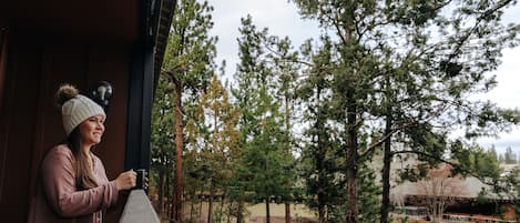 Une personne se tient près d’une rambarde en bois, d’où elle a une vue sur une rivière et des arbres.