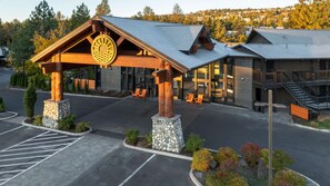 A lodge with a prominent wooden structure and stone base, featuring outdoor seating and a clear view of the surrounding forest. - Riverhouse Lodge (Bend)