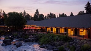 A riverside hotel with outdoor seating and a bridge.