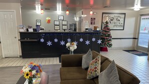 A lobby with a reception desk, a Christmas tree, a brown sofa, and a coffee table with flowers.