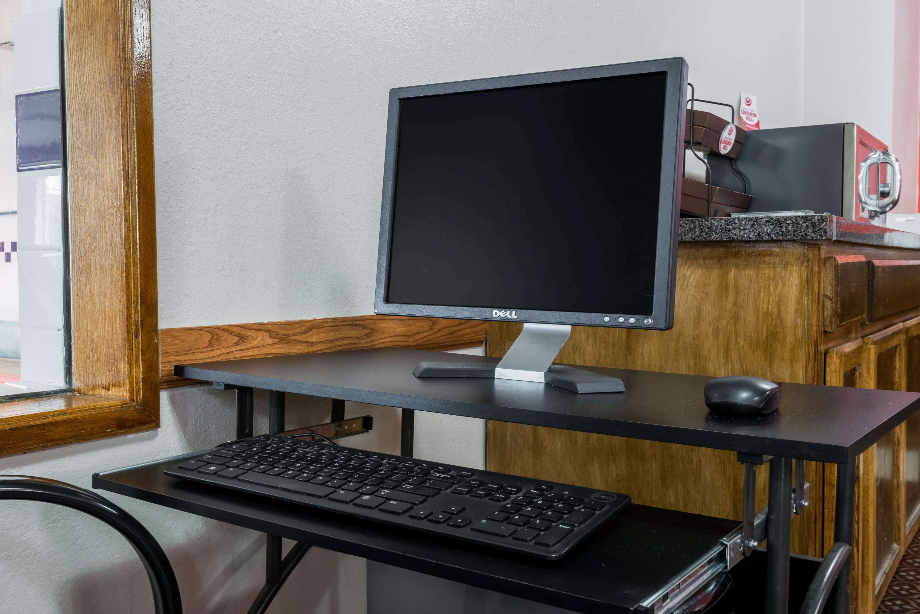 A computer desk with a Dell monitor, keyboard, and mouse.