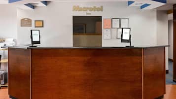 Ein Empfangsschalter mit Holzoptik, ein Schild darüber mit der Aufschrift 'Microtel Inn' und zwei digitale Kioske auf beiden Seiten.
