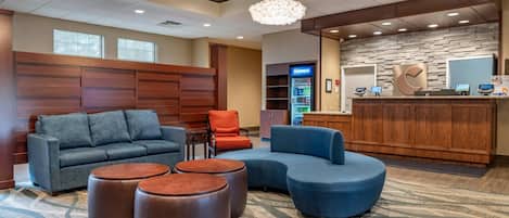 A lobby with a reception desk, seating area, and a Pepsi refrigerator.