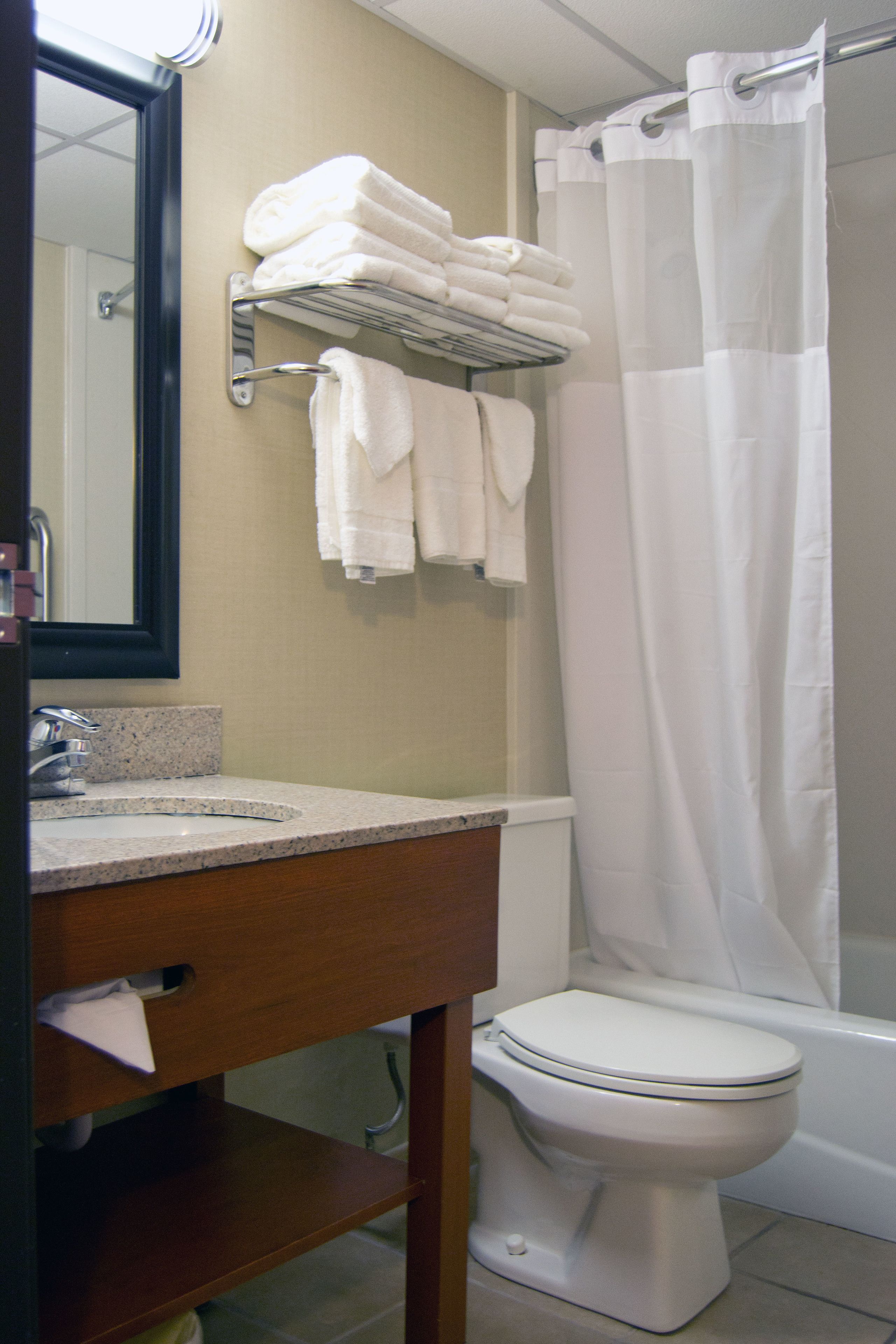 A bathroom with a sink, mirror, towel rack, and toilet.