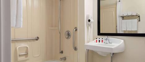 A bathroom with a bathtub, a shower, a sink, and a mirror.