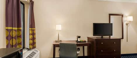 Una habitación de hotel con escritorio, silla, televisión, cómoda y cama.