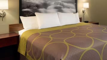 Una habitación de hotel con una cama, dos lámparas de noche, una obra de arte en la pared y una colcha estampada.