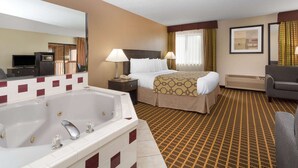 A hotel room with a large bathtub, two beds, a sofa, and a TV. - Baymont by Wyndham Harvard (Harvard)