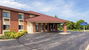 A two-story hotel with a brick facade, a covered entrance, and a parking lot. - Baymont by Wyndham Harvard (Harvard)