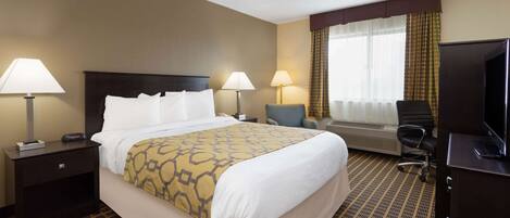 A hotel room with a large bed, two bedside tables with lamps, a desk with a television, and a chair.
