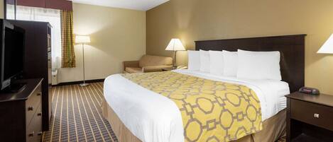 A hotel room with a large bed, a desk with a television, a chair, and two bedside lamps.
