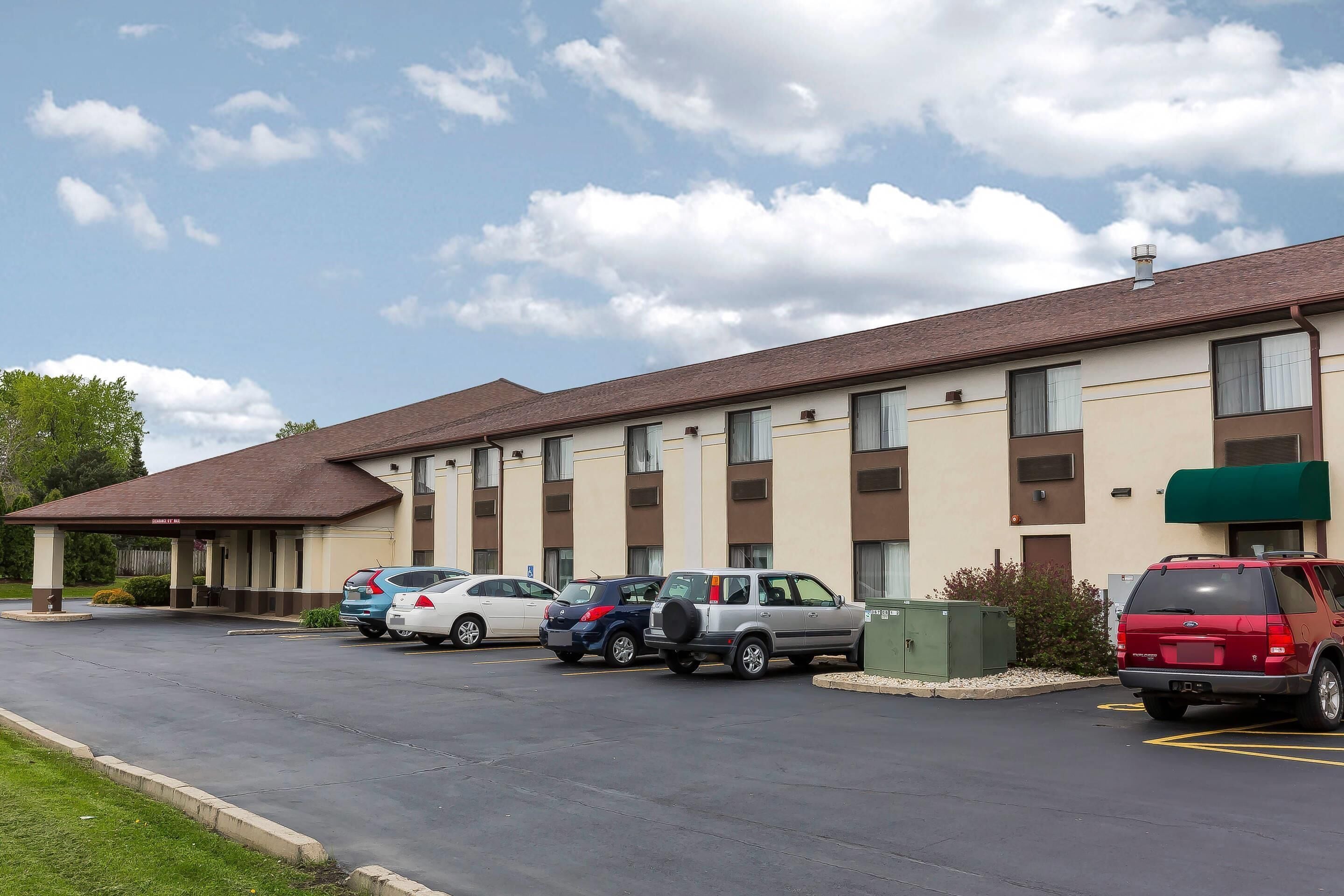 A motel with a parking lot and a covered entrance.