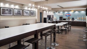 A modern bar area with a long counter, multiple stools, and a coffee machine. - Baymont by Wyndham Boardman (Boardman)
