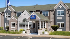 A multi-story hotel with a prominent American flag, a Baymont sign, and a well-maintained exterior. - Baymont by Wyndham Boardman (Boardman)