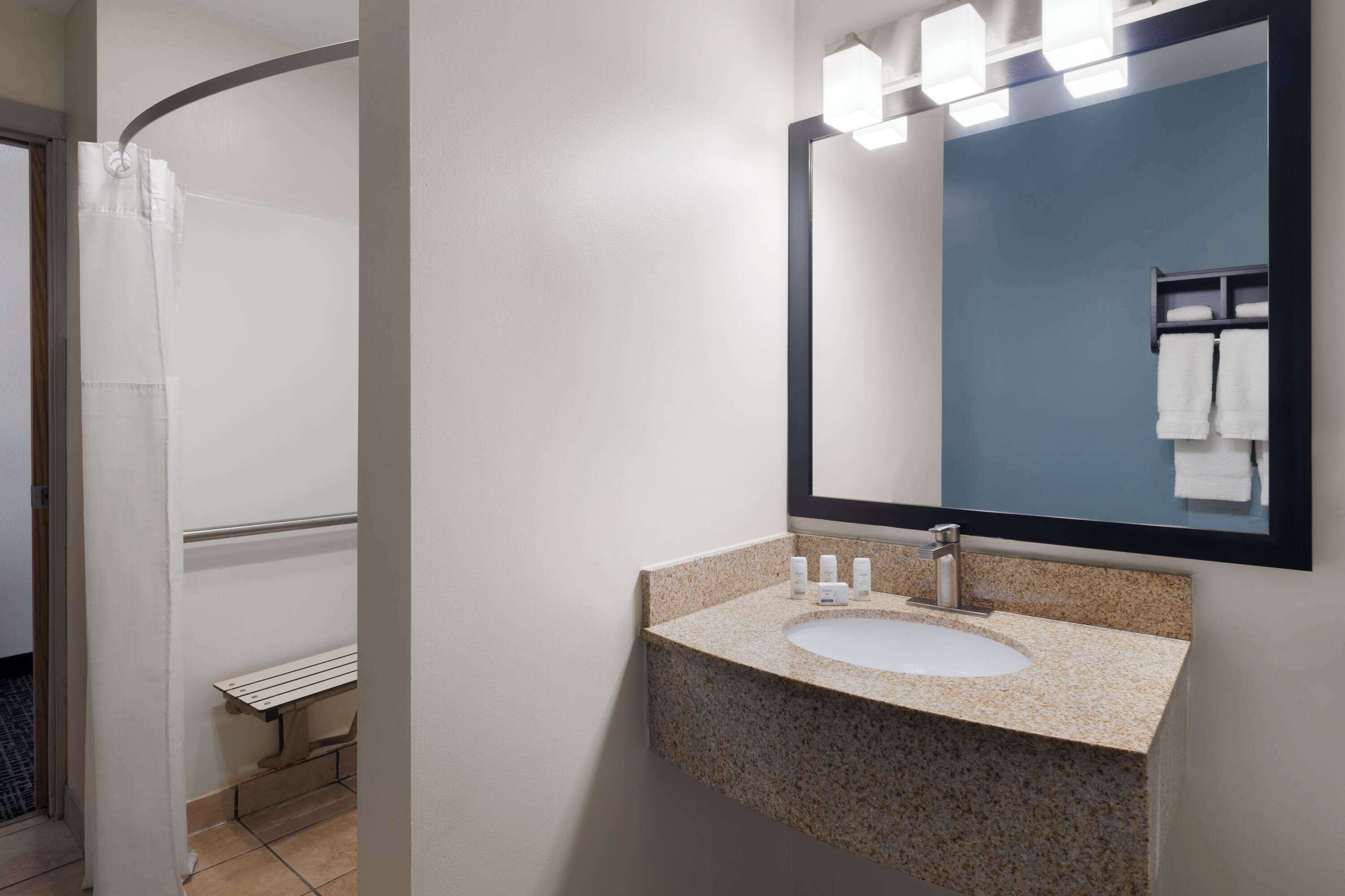 A bathroom with a sink, mirror, and shower curtain.