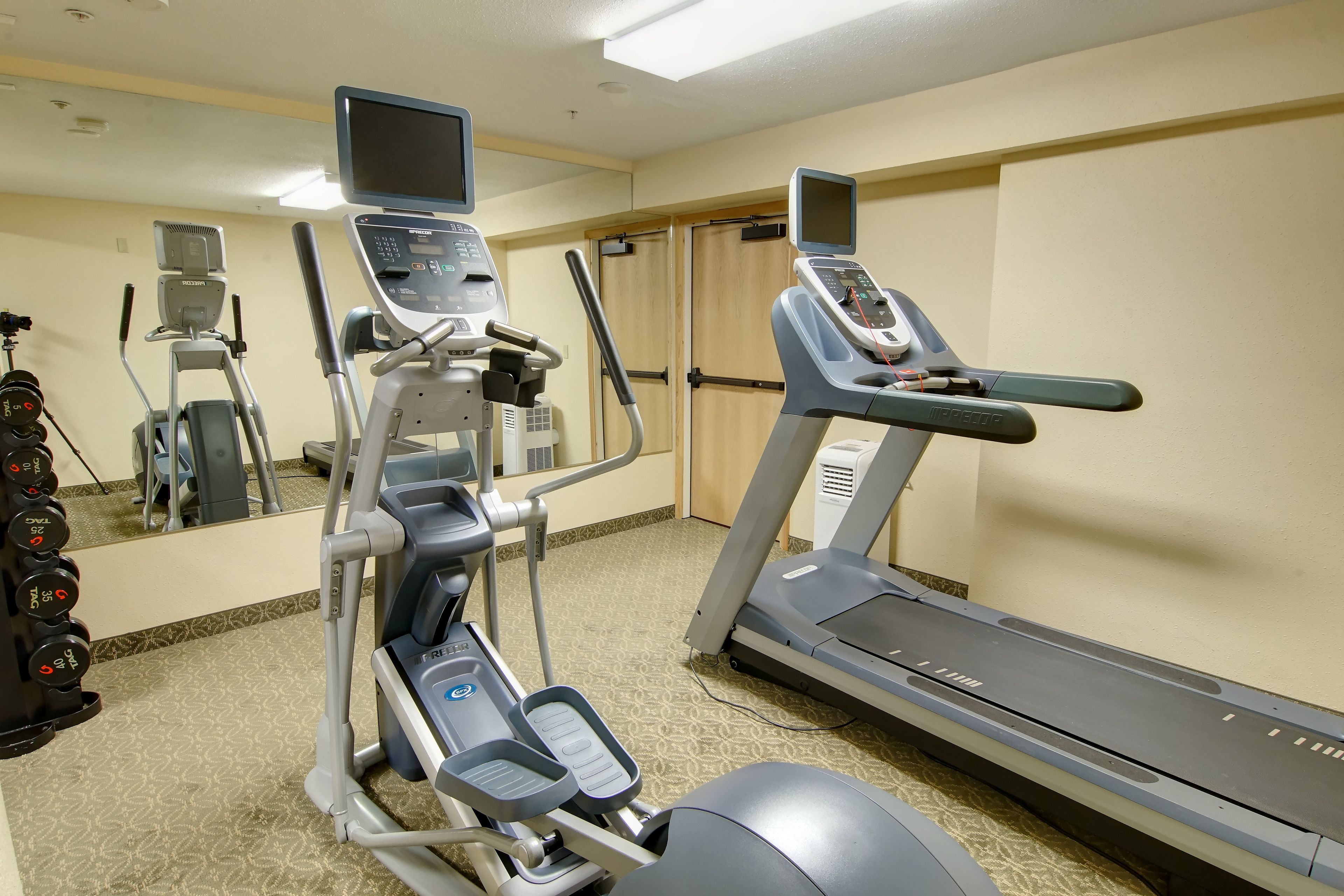 Un gimnasio con cintas de correr, una máquina elíptica y una bicicleta estática.