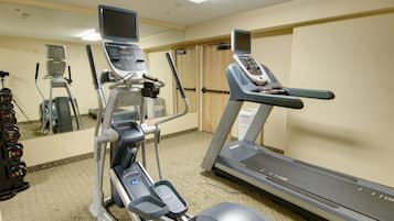 Un gimnasio con cintas de correr, una máquina elíptica y una bicicleta estática.