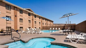 A hotel pool area with lounge chairs, umbrellas, and a pool with blue tiles.