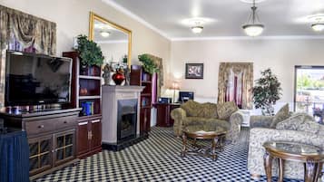Una sala de estar con piso a cuadros, una chimenea, un televisor, un sofá y una mesa de centro.