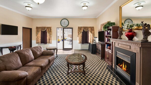 A living room with a leather sofa, a round glass table, a fireplace, and a large mirror.
