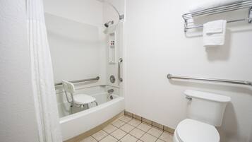 A bathroom with a bathtub, toilet, and a handrail.