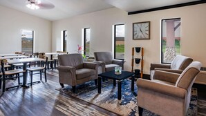 A spacious living room with a large dining table, comfortable seating, and large windows offering views of the outdoors. - Super 8 by Wyndham Spokane Valley (Spokane Valley)