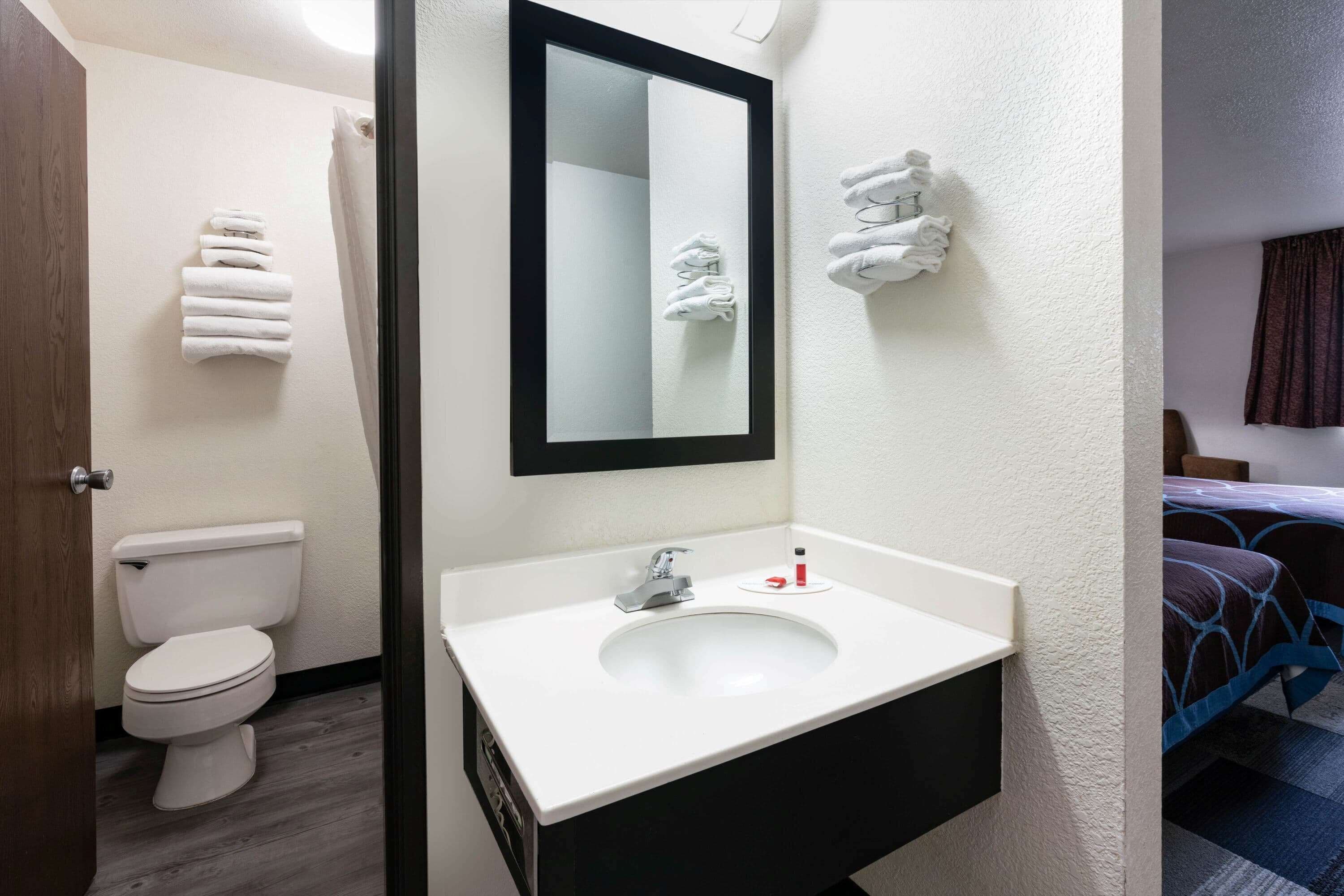 A bathroom with a white sink, a mirror, and towels on the wall.