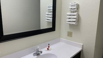 A bathroom with a white sink, a mirror, and a towel rack with folded towels.
