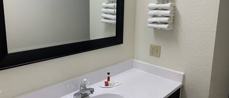 A bathroom with a white sink, a mirror, and a towel rack with folded towels.