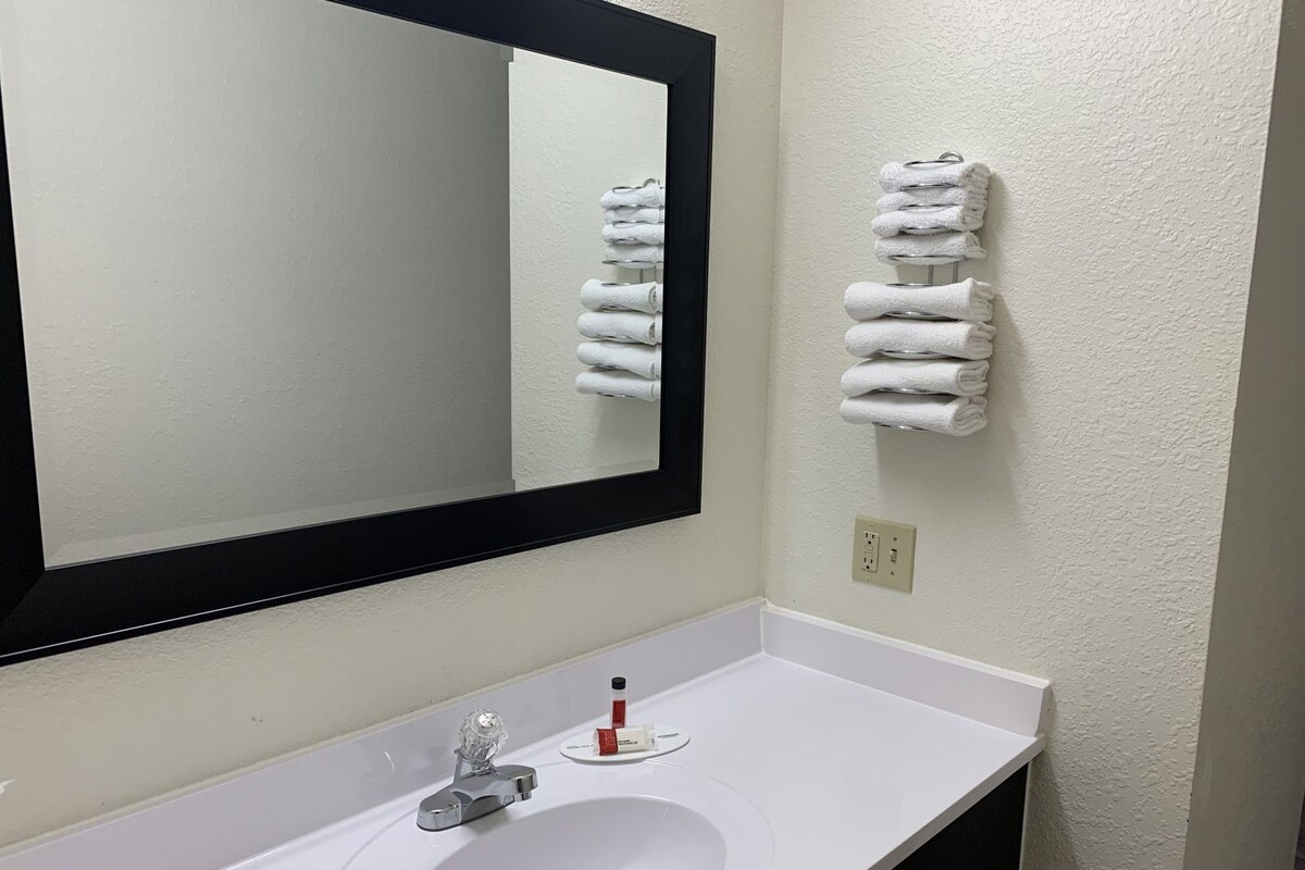 A bathroom with a white sink, a mirror, and a towel rack.