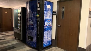 Una máquina expendedora con botellas de agua Aquafina, una puerta con el símbolo de número y un piso alfombrado.