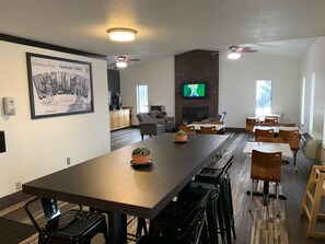 Enjoy meals with friends and family in this spacious dining area, featuring a long table, fireplace, and comfortable seating.