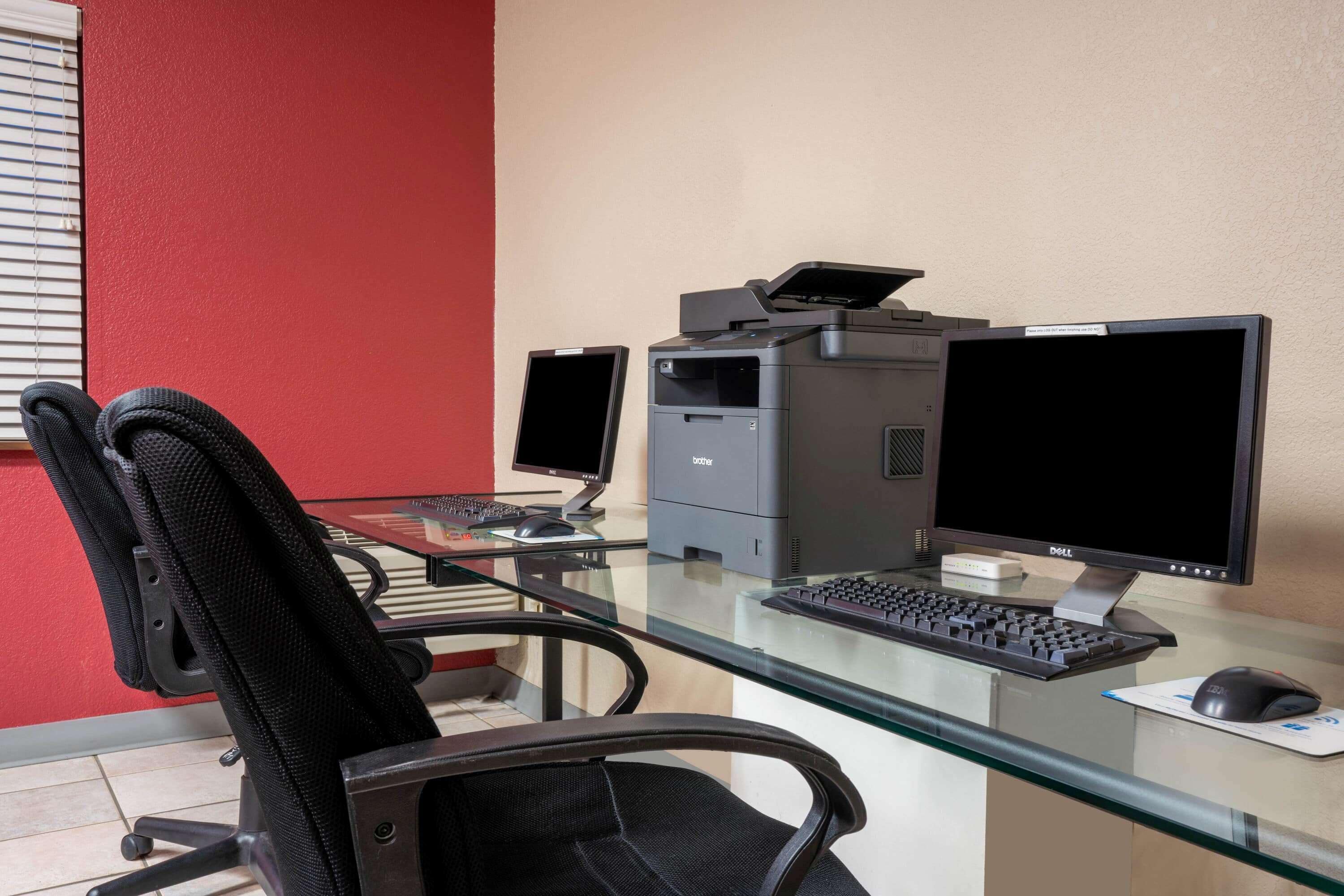 A home office setup with a desk, two monitors, a printer, a keyboard, a mouse, and a chair.
