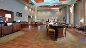 A spacious lobby with a central bar area, multiple seating arrangements, and a reception desk.