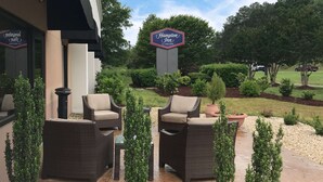 A Hampton Inn by Hilton sign, outdoor wicker furniture, and landscaped garden.
