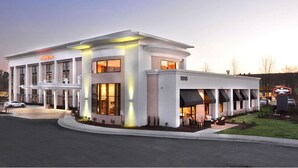 A hotel with a classic architectural design, featuring a prominent entrance, a covered outdoor seating area, and a well-lit facade.