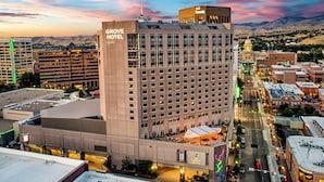 Um hotel com uma placa chamativa, uma garagem de estacionamento e vista para o horizonte urbano.