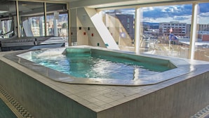 Uma banheira de hidromassagem com vista para o horizonte urbano através de grandes janelas.