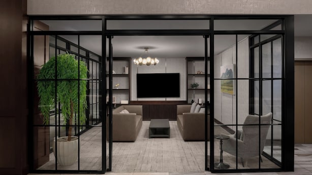 Uma sala de estar moderna com uma TV de tela plana, dois sofás, uma mesa de centro e um vaso com planta.