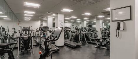 A gym with various exercise equipment, including treadmills and stationary bikes, arranged in rows.