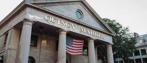 The Quincy Market building with its neoclassical architecture, prominent columns, and the American flag displayed.