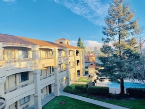 A multi-story hotel with balconies, a swimming pool, and a large tree in the foreground. - Good Nite Inn Fremont (Fremont)