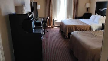 Una habitación de hotel con dos camas, un escritorio, una silla, un televisor y una ventana con cortinas.