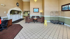 A lobby with a reception desk, seating area, and a chandelier.
