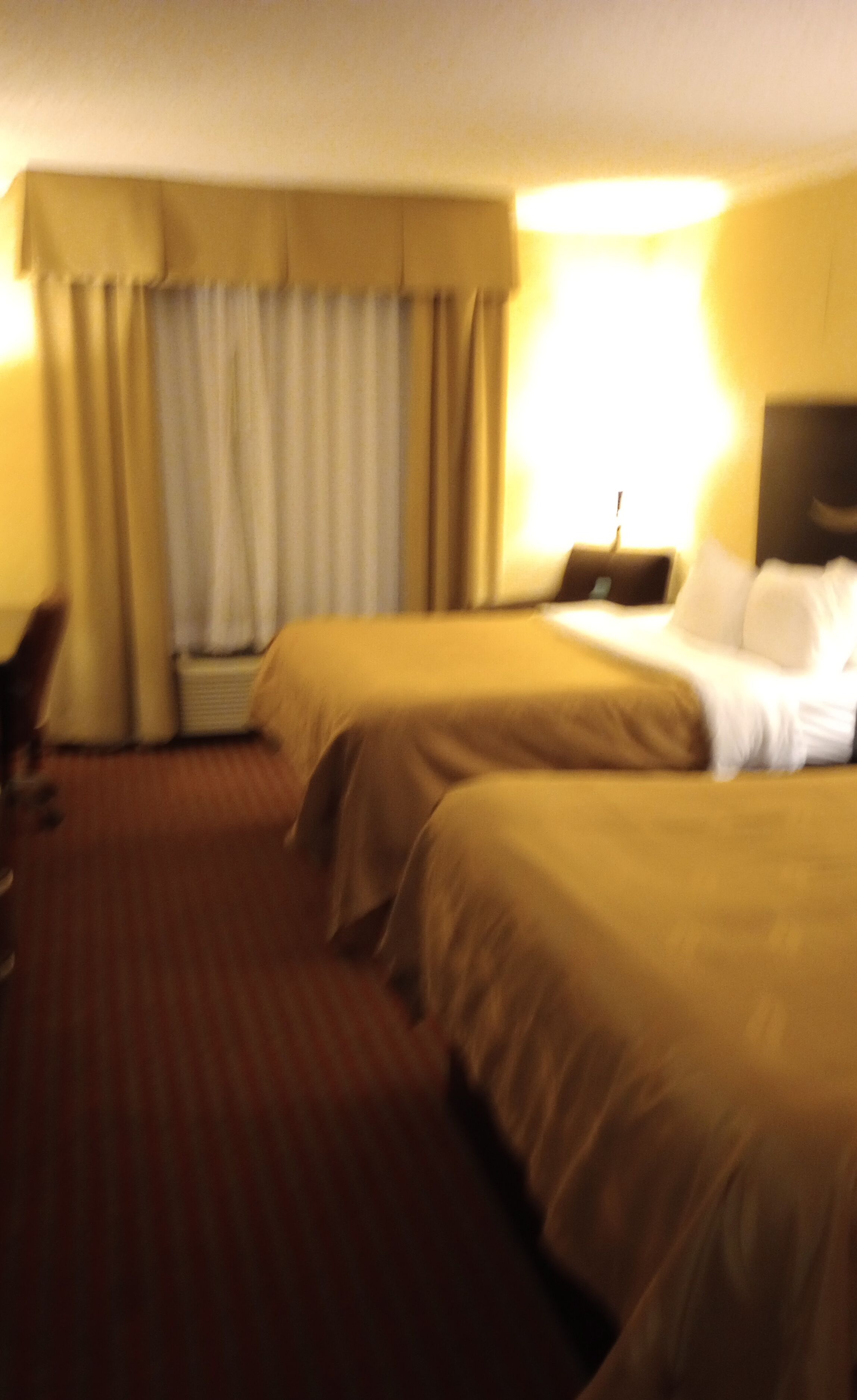 A hotel room with two beds, a desk, and a chair.