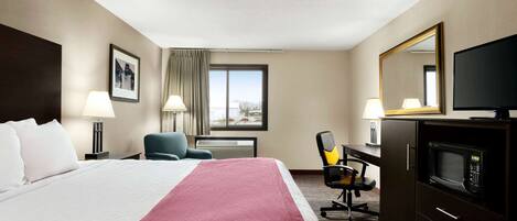 A hotel room with a bed, a desk, a chair, a TV, and a microwave.