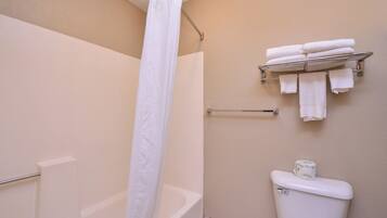 A bathroom with a bathtub, a toilet, and a towel rack with folded towels.
