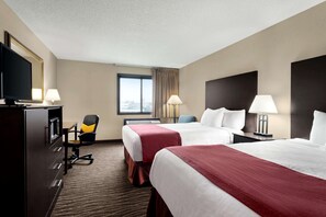 A hotel room with two beds, a desk, a chair, a TV, and a window with curtains. - Baymont by Wyndham Sioux Falls West (67058) Sioux/ Near Airport (Sioux Falls)